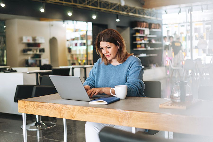 Business Insurance - Portrait of a Female Small Business Owner Sitting in Her Beauty Salon While Using a Laptop